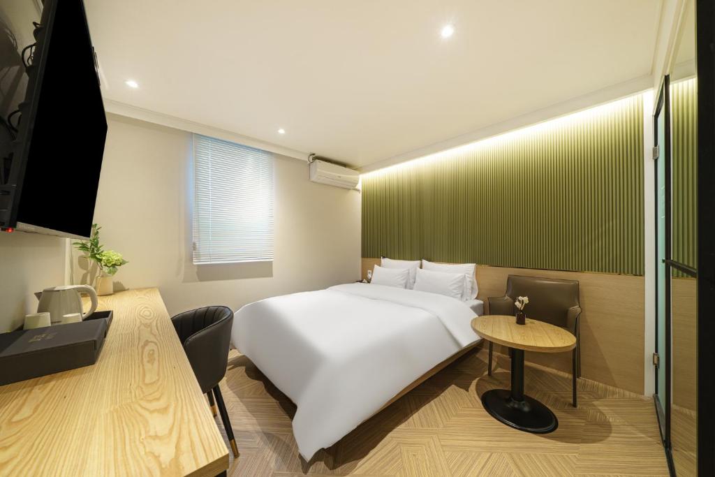 仁川市No 25 Hotel Dongam Branch的卧室配有白色的床和桌子