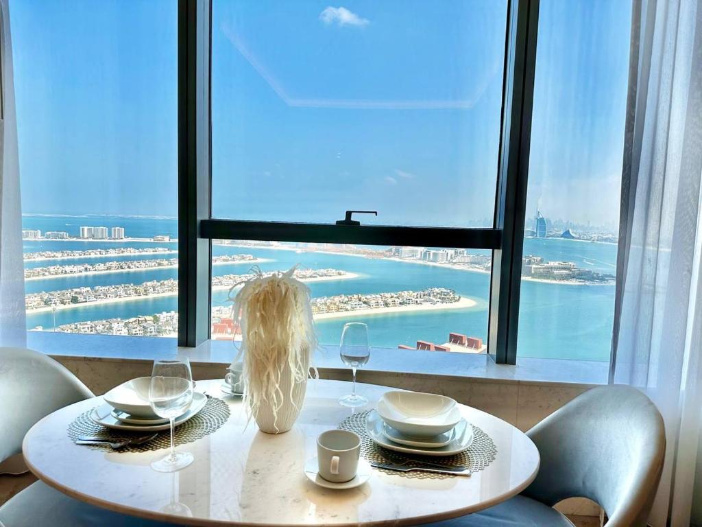 迪拜Luxury Studio in High Floor Full Sea View in The Palm Tower Plam Jumeirah的窗户前带盘子和酒杯的桌子