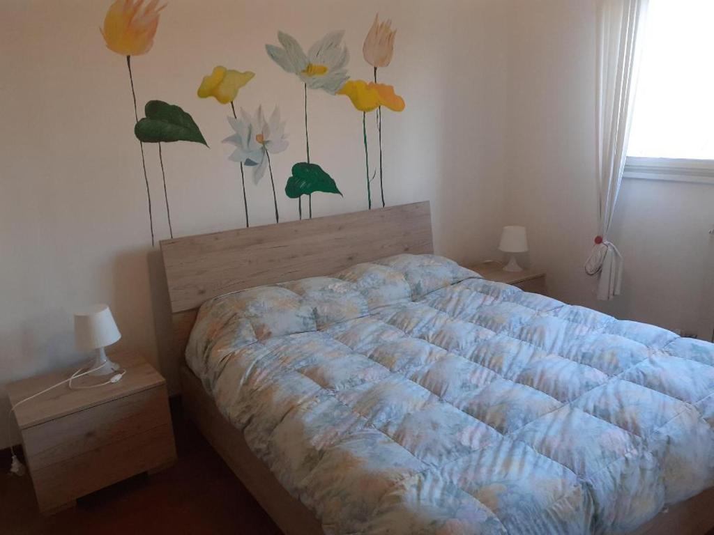 米兰La Casa di Boh, vicino ospedale San Paolo, Iulm, Forum Assago的卧室配有一张挂有花卉画的床铺。