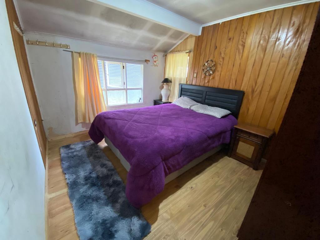 柴滕La cabaña的一间卧室设有紫色的床和窗户