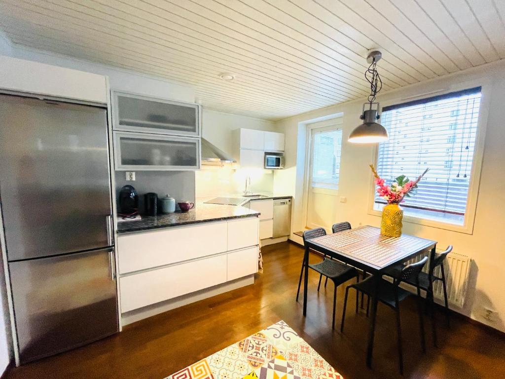 拉赫蒂Kaunis kattohuoneisto Lahden keskustassa的厨房配有桌子和不锈钢冰箱。