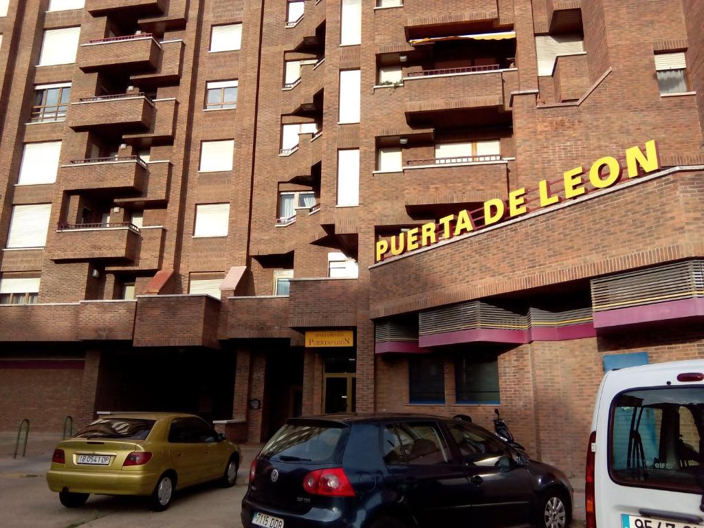 莱昂莱昂图里斯迪克普埃尔塔公寓酒店的两辆汽车停在大楼前