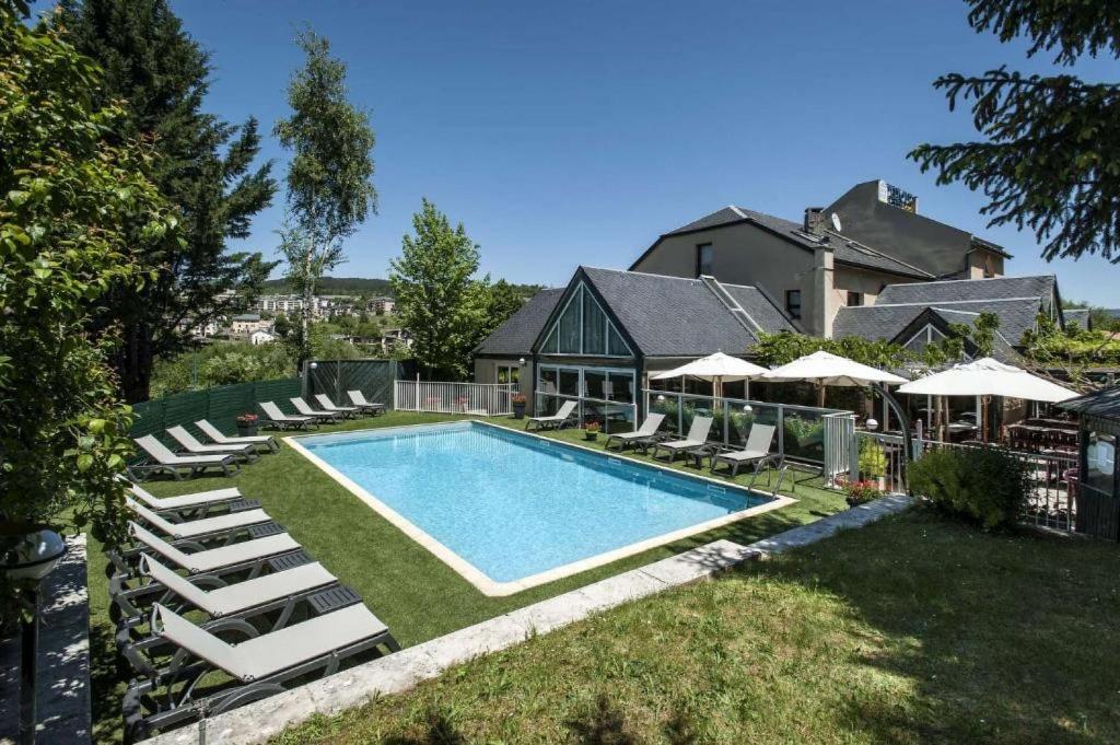 芒德Brit Hotel Confort Deltour Mende的一个带躺椅的游泳池以及一座房子
