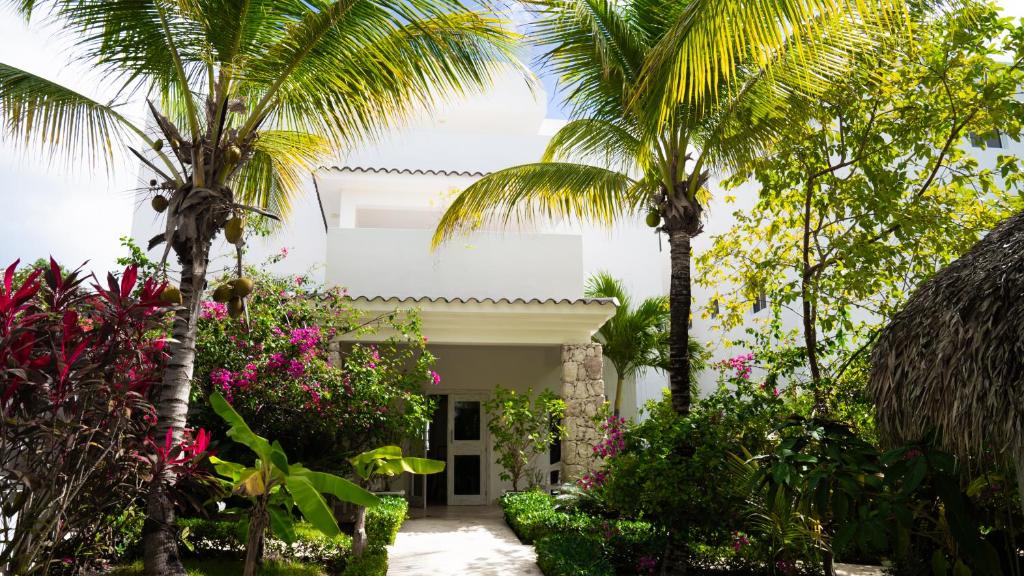 蓬塔卡纳Boutique Hotel Las Flores Punta Cana的棕榈树和鲜花的白色房子