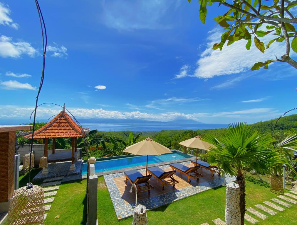 BatununggulMere Sea View Resort & Spa的一个带椅子和遮阳伞的游泳池以及大海