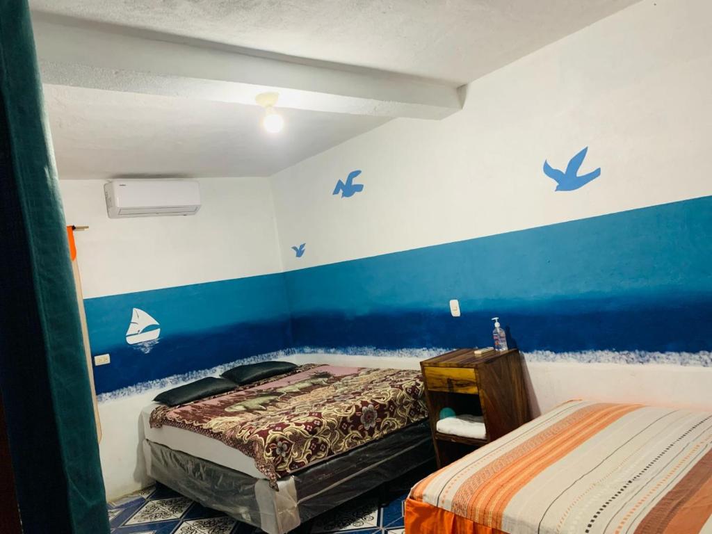 El Paredón Buena VistaCuarto Cactus的一间卧室设有两张床,拥有蓝色的墙壁。