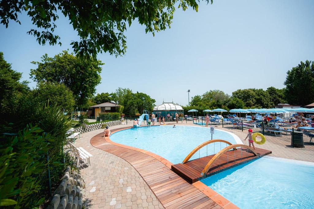 圣马力诺Glamping San Marino的旁边设有木制长凳的大型游泳池