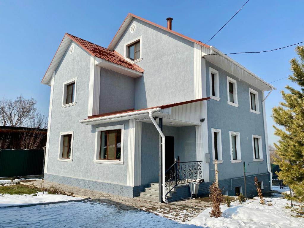 阿拉木图Askarov House的雪中的一个蓝色和白色的房子