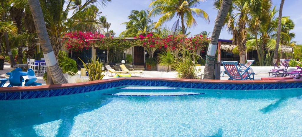 棕榈滩Beach House Aruba Apartments的一个带椅子的游泳池,棕榈树
