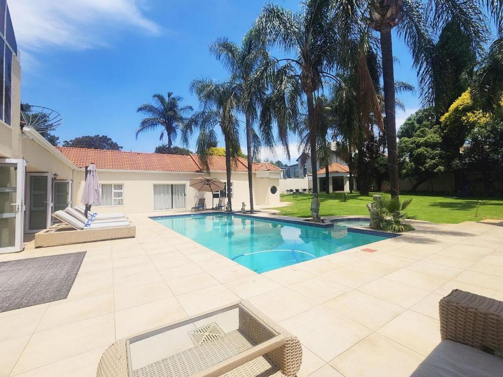 BedfordviewVilla Reis - The Villa of Kings的棕榈树庭院内的游泳池