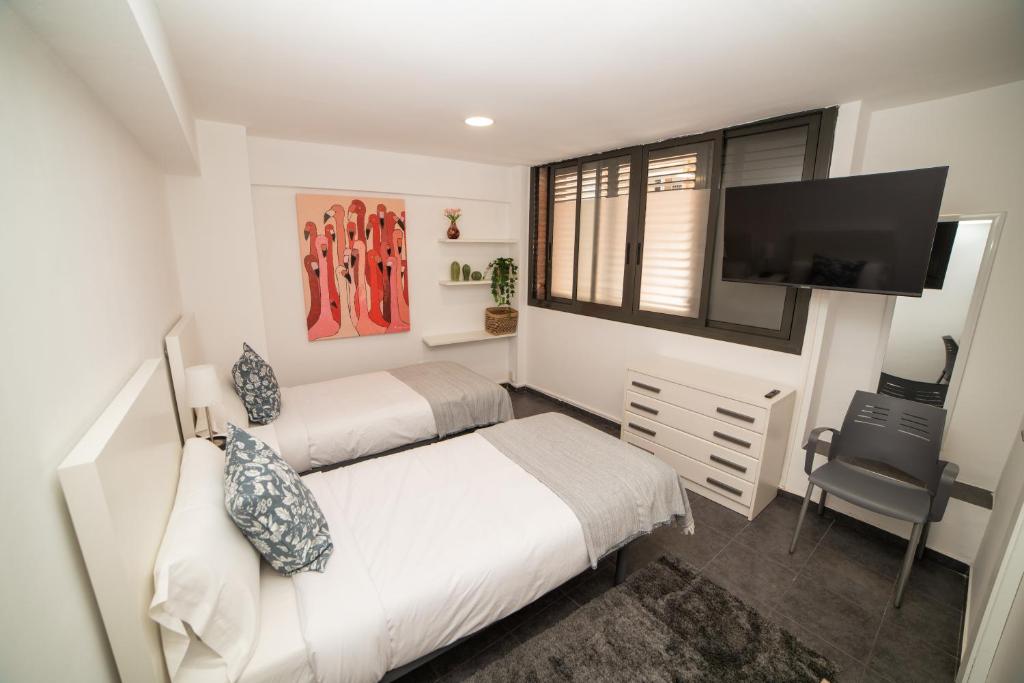 巴塞罗那Barcelona Apartment Near Park Güell的一间卧室配有两张床和一台平面电视