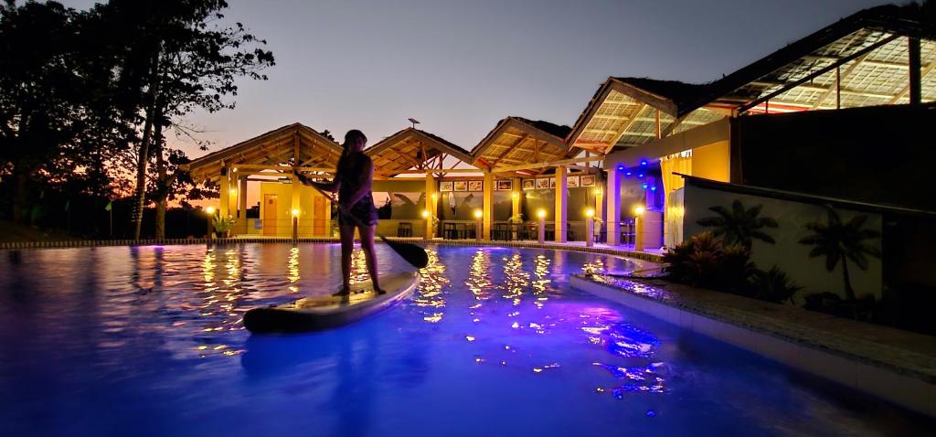 FerrolAnnabel's Resort的一个人在晚上站在游泳池的桨板上