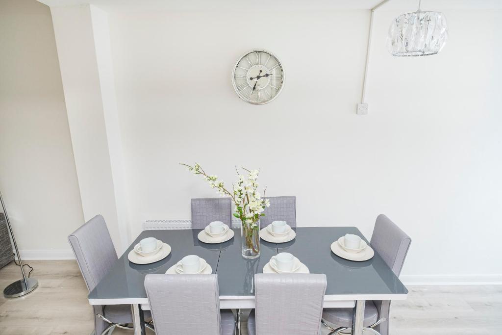 雷纳姆Heads-On-Beds Rainham Essex - 4Bedrooms with Garden的蓝色的餐桌、椅子和时钟