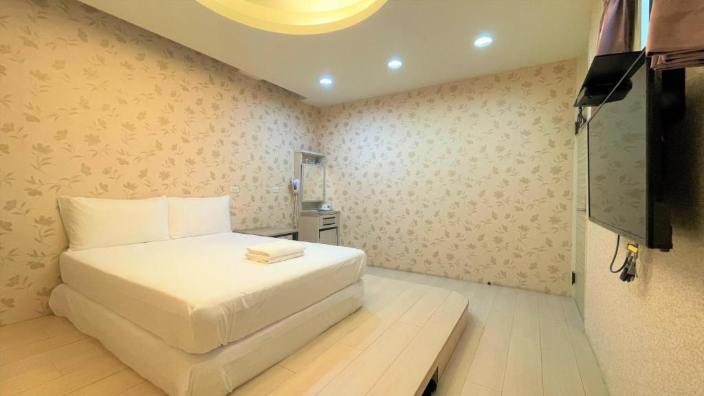 Hsia-shih-pi逢甲馨宿的卧室配有白色的床和平面电视。