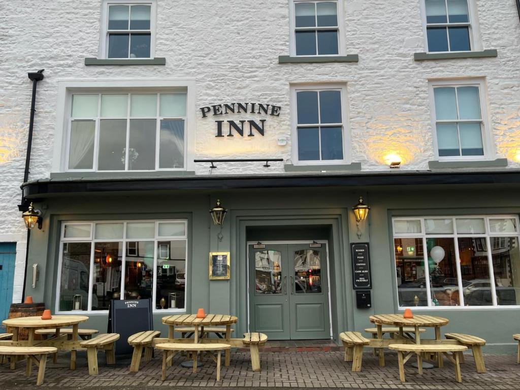 柯比斯蒂芬The Pennine Inn的前面设有野餐桌的建筑