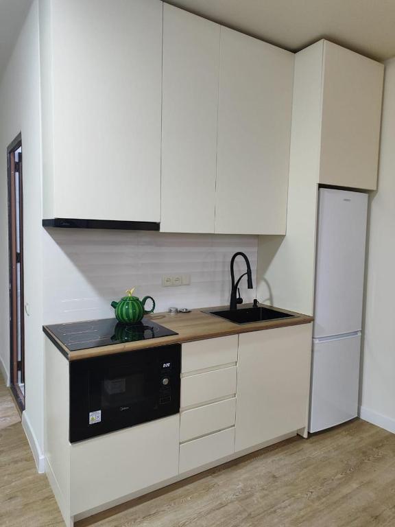 巴统Almare Batumi的厨房配有白色橱柜、水槽和冰箱。