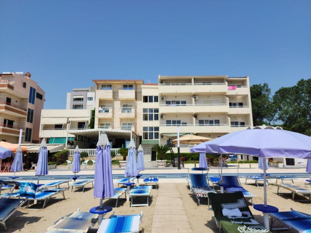 都拉斯Hotel Maren Durres的一个带蓝色躺椅和遮阳伞的游泳池