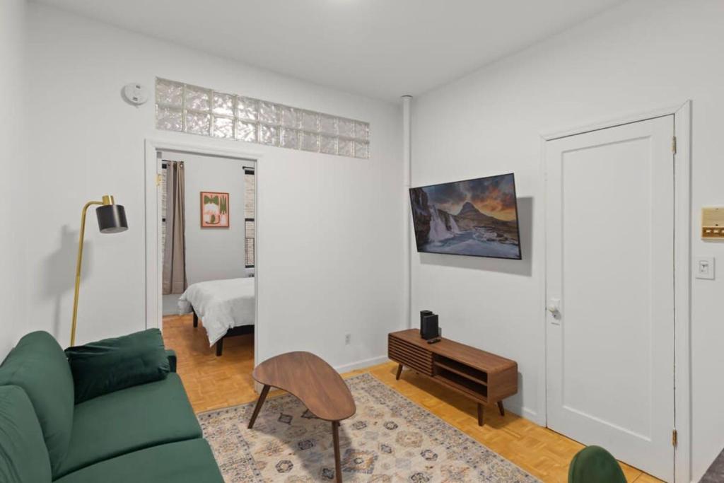 纽约Cozy 1BR in the Upper East Side的客厅配有绿色沙发和床。