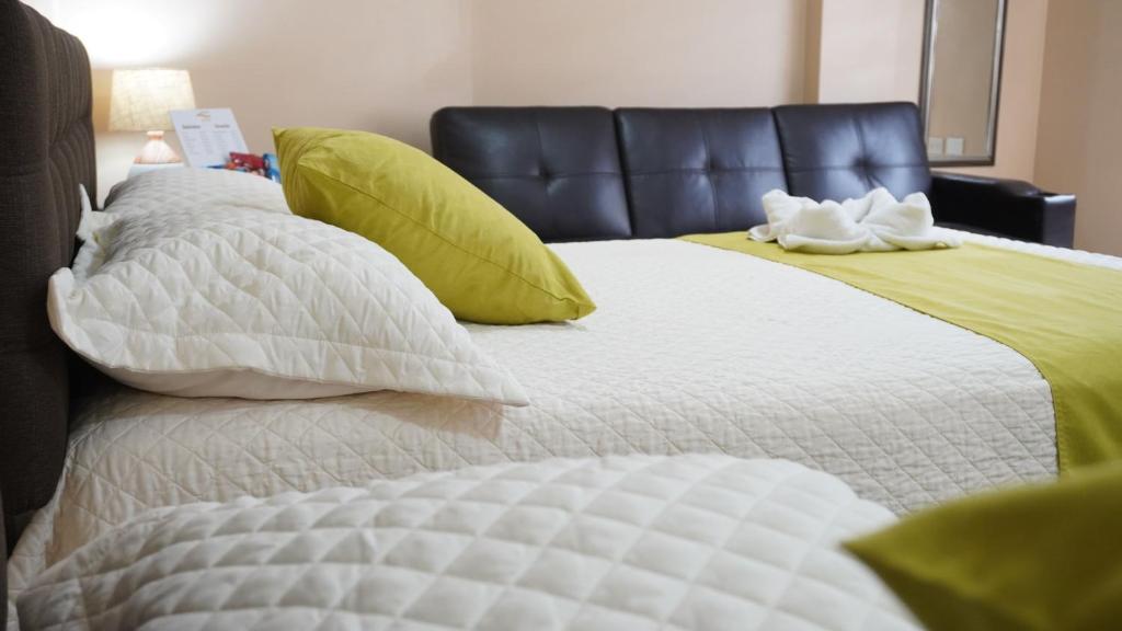 曼塔YORMARI HOTEL的一张带白色床单和绿色枕头的床