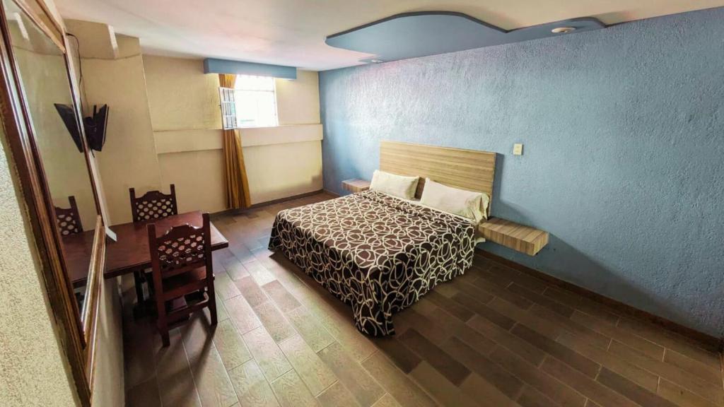 墨西哥城Hotel Plaza San Juan的酒店客房设有一张床铺、一张桌子和一张桌子。