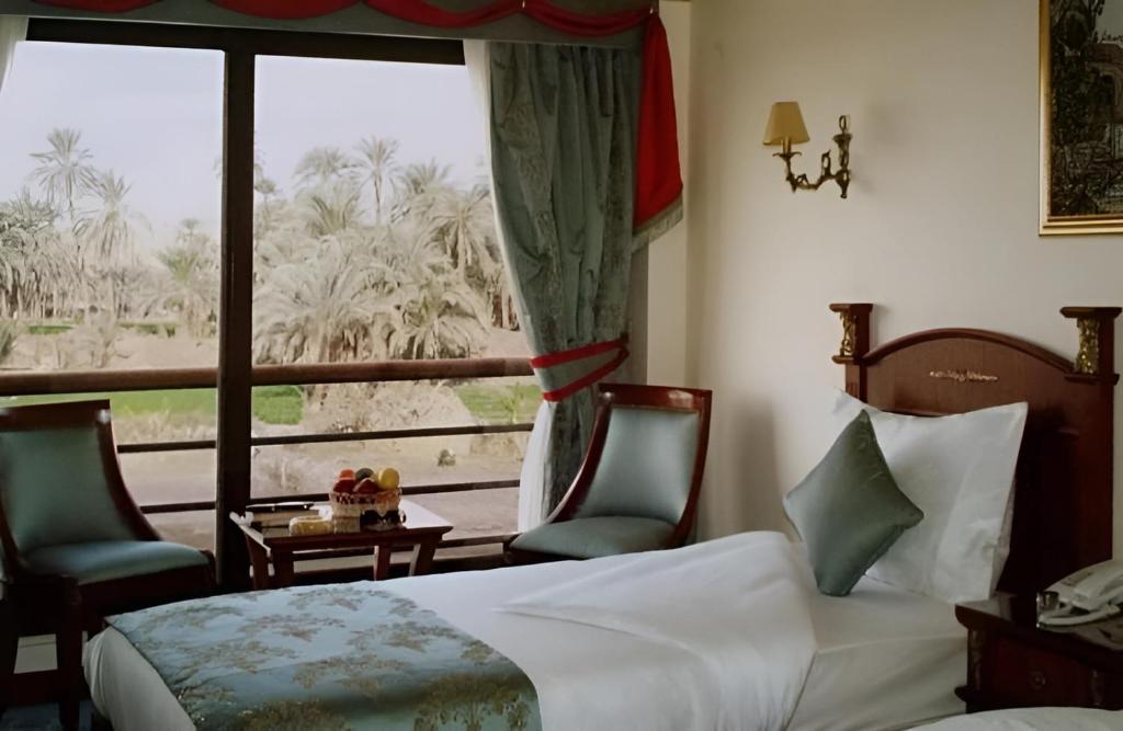 阿斯旺NILE CRUISE LUXOR & AsWAN نايل كروز الاقصر و اسوان的一间卧室配有一张床、两把椅子和一个窗户
