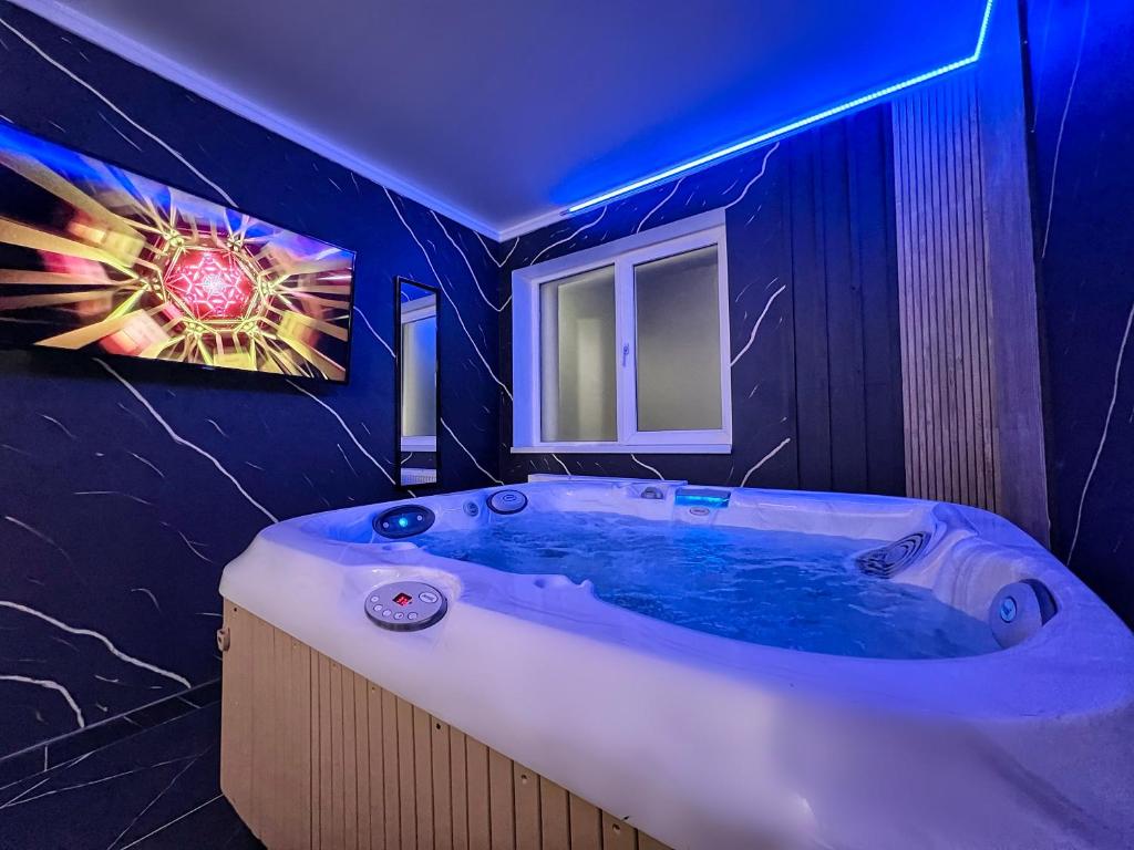锡比乌Luxor - Jacuzzi&Cozy Apartments的浴室配有蓝色灯光的大浴缸