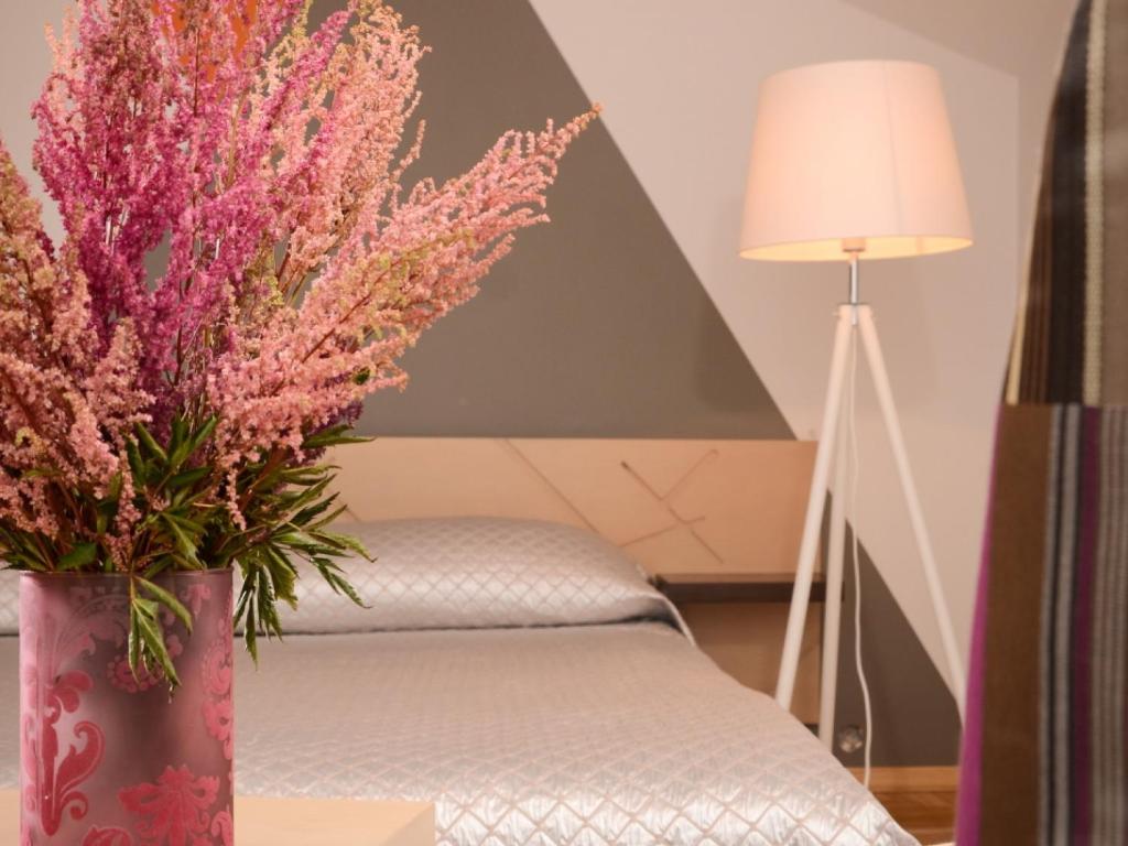 萨尔杜斯Mans Nams - self check in hotel的一张桌子上一束粉红色的花瓶,旁边是一张床
