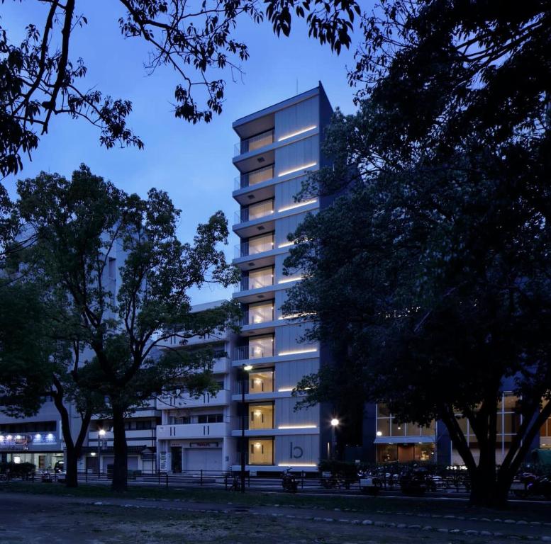 广岛bHOTEL Heiwaoodori 401 - Brand New Apt Famous Hiroshima Dori 6ppl的一座高大的公寓楼,晚上灯光照亮