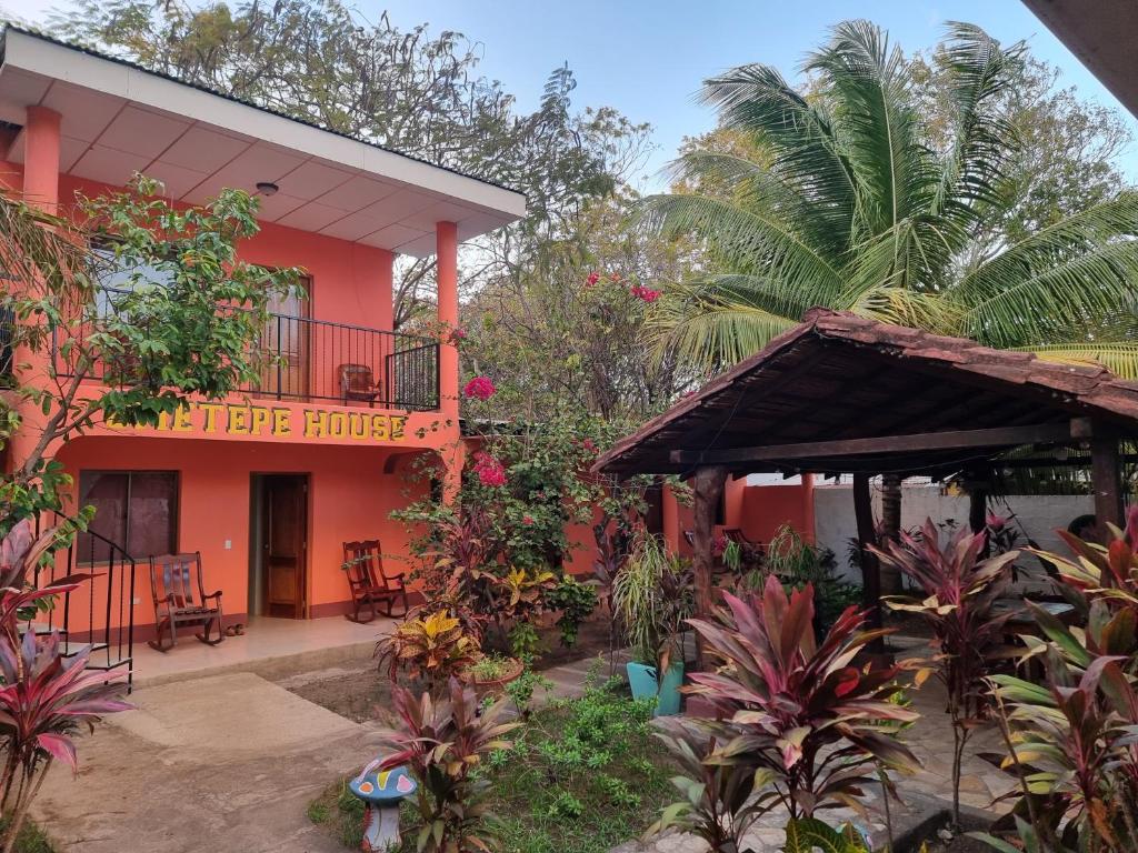 莫约加尔帕Ometepe House的一座橙色的建筑,设有阳台和棕榈树