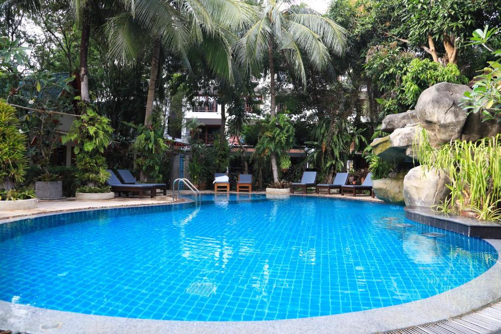 拉威海滩Phuket Meet Holiday Hotel 普吉岛相遇酒店的棕榈树度假村内的游泳池