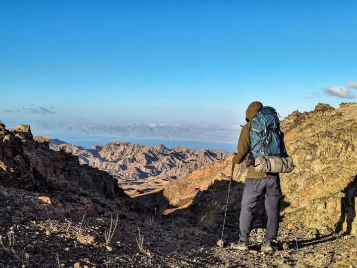达纳Adventure camping - Organized Trekking from Dana to Petra的背着背包站在山顶的人