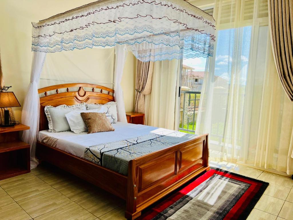 KigoFully furnished 3 bedroom apartment in Mirembe Villas Kigo, Uganda的一间卧室设有天蓬床和窗户。