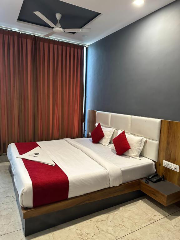 苏拉特Hotel Dumas Near Airport的一间卧室配有一张带红色枕头的大床