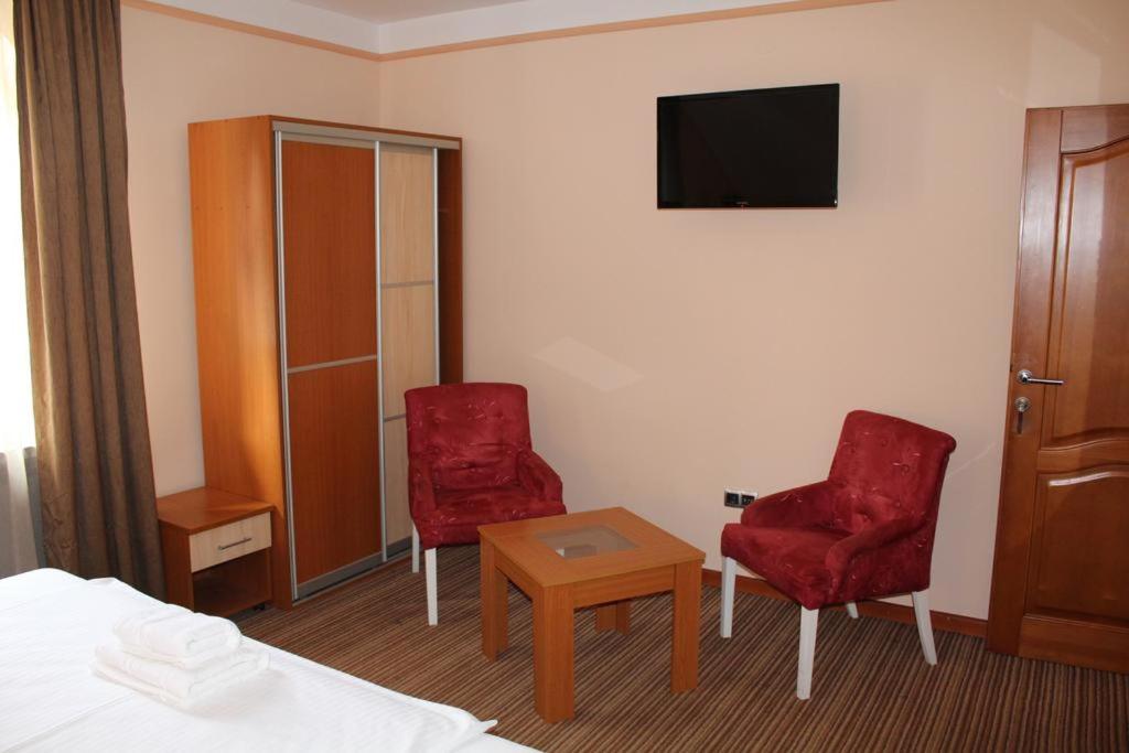 图兹拉Motel Royal的酒店客房设有2把红色椅子和电视
