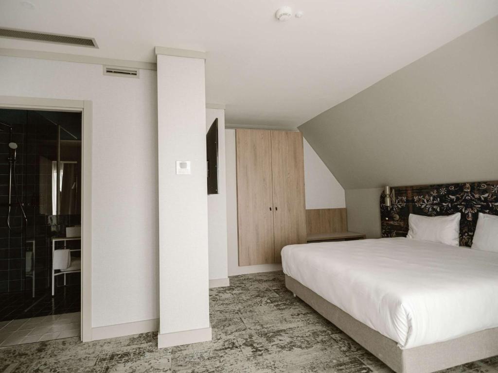 锡比乌Mercure Sibiu Arsenal的一间带白色大床的卧室和一间浴室