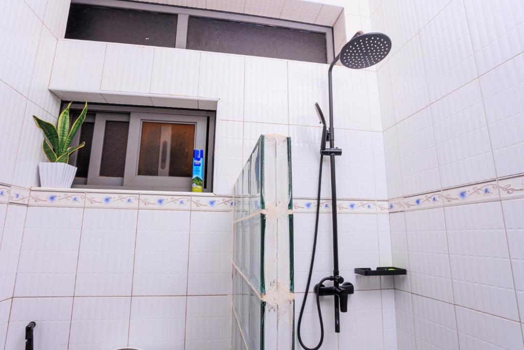 坎帕拉Greenwoods Apartments的白色瓷砖浴室设有淋浴和窗户