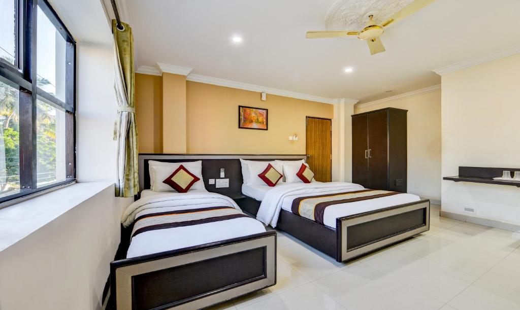 钦奈Hotel Saibala Inn的一间卧室设有两张床和窗户。