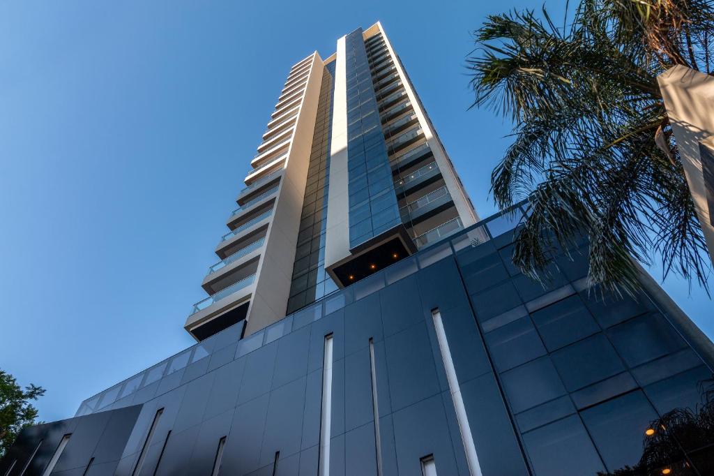 亚松森ÚNICO - Stay & Residences by AVA的一座高大的建筑,背后是蓝天