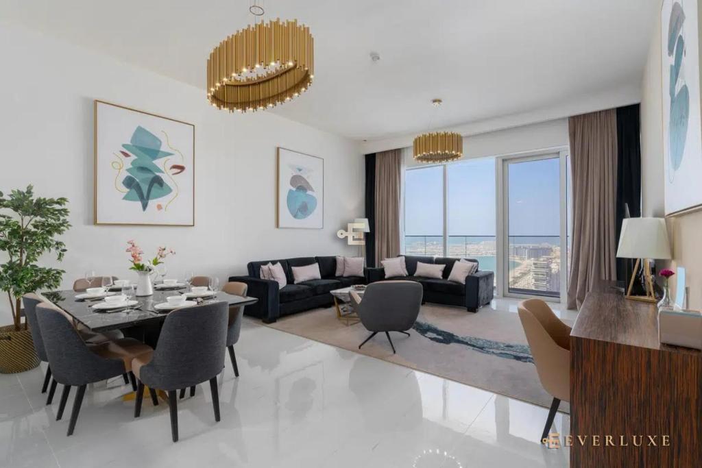迪拜Everluxe Palm Views 3 Bedroom的客厅配有餐桌和沙发
