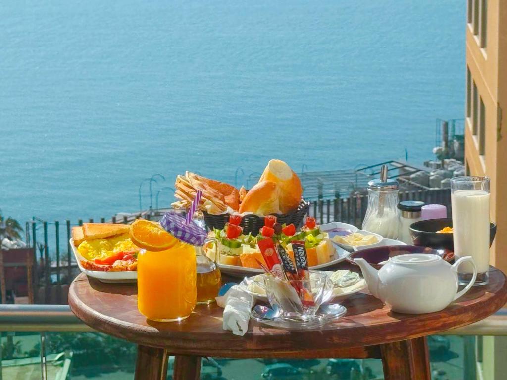 贝鲁特国王套房酒店 的一张桌子,在阳台上提供早餐食物,阳台上享有海景