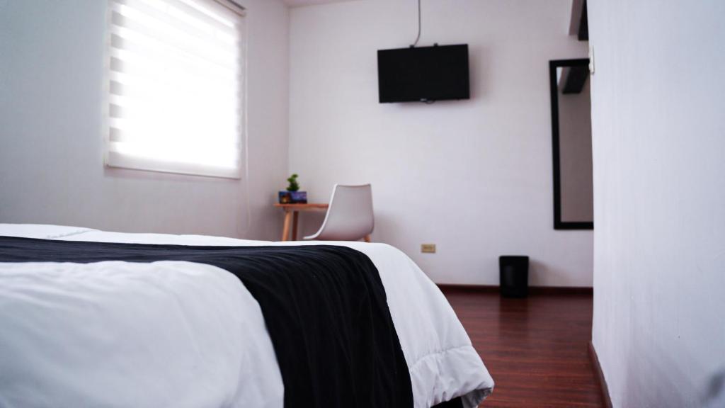昆卡Casa Roja Residencia 10-51的卧室配有一张床,墙上配有电视