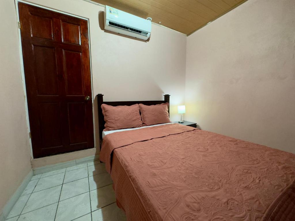 奎波斯城Casa Quepos的一间卧室配有一张带红色毯子和门的床
