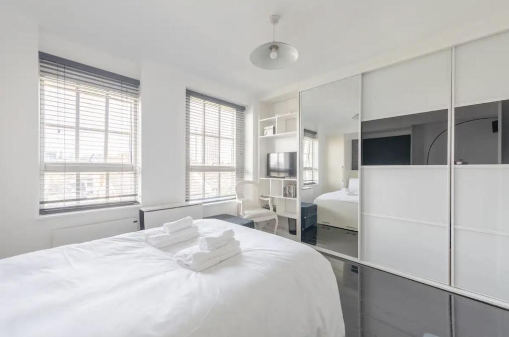 伦敦Cosy Studio in Bethnal Green的白色卧室配有一张大白色床和2条毛巾