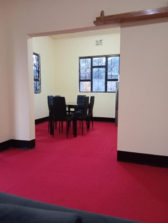 Boma la NgombeKilimanjaro Homestay的一间铺有红地毯并配有桌椅的房间