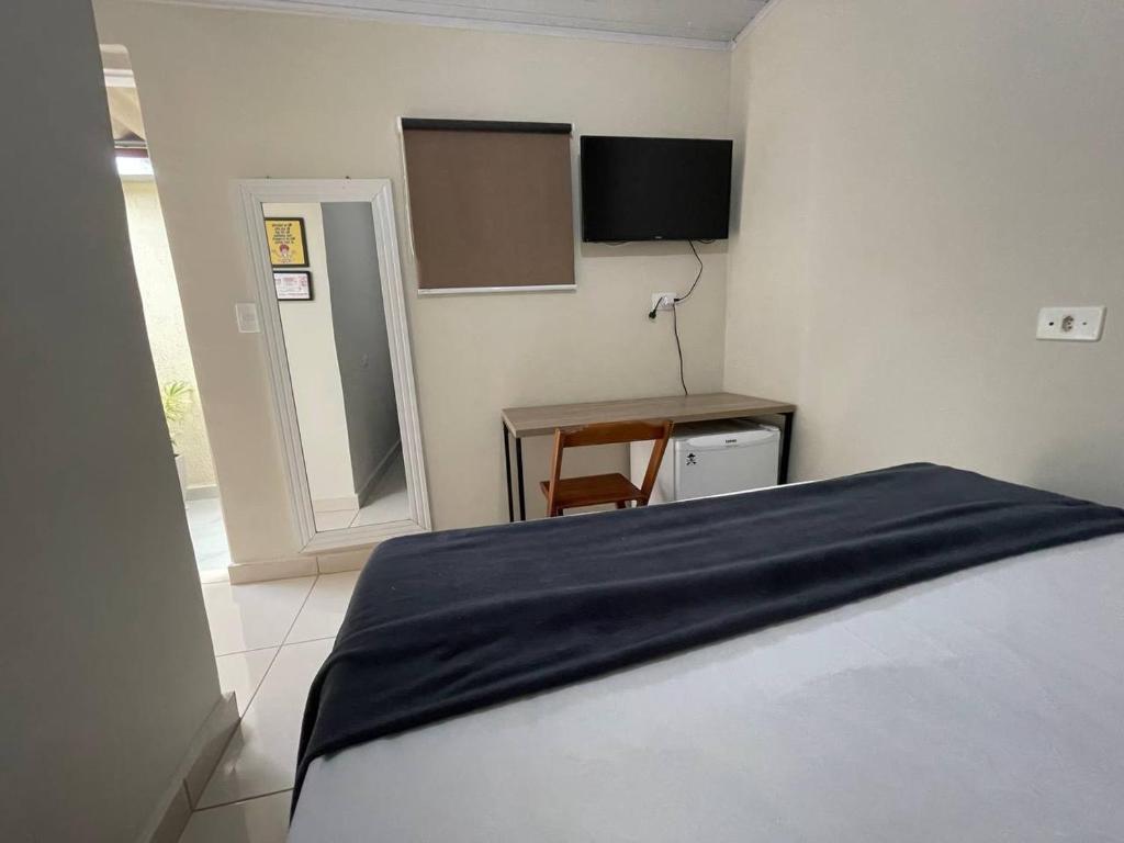 瓜鲁柳斯Hostel Quartos com banheiro individual perto do Aeroporto的一间卧室配有一张床、一张桌子和一面镜子