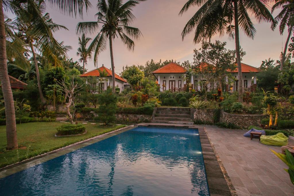 珀尼达岛De Casa Ananda Nusa Penida的一座带游泳池和棕榈树的房子