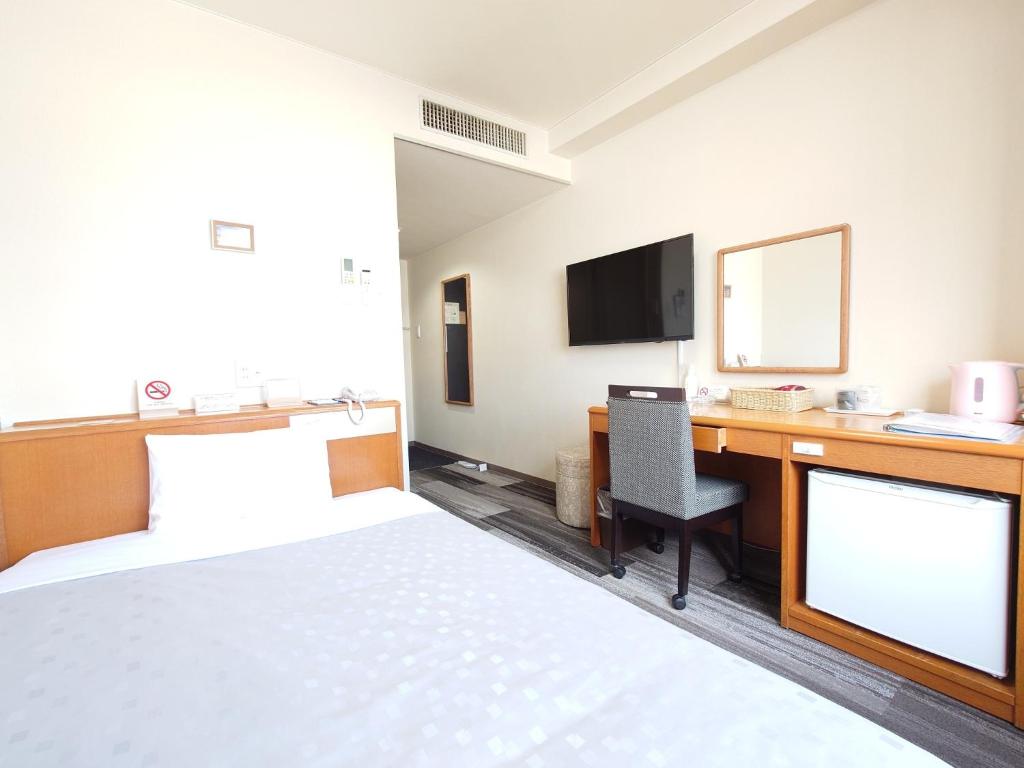 冈山SAIDAIJI GRAND HOTEL - Vacation STAY 92835的酒店客房配有一张床和一张书桌及一台电视