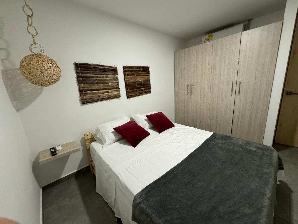 卡利Apartamentos Area Medica Imbanaco的一间卧室配有带白色床单和红色枕头的床。