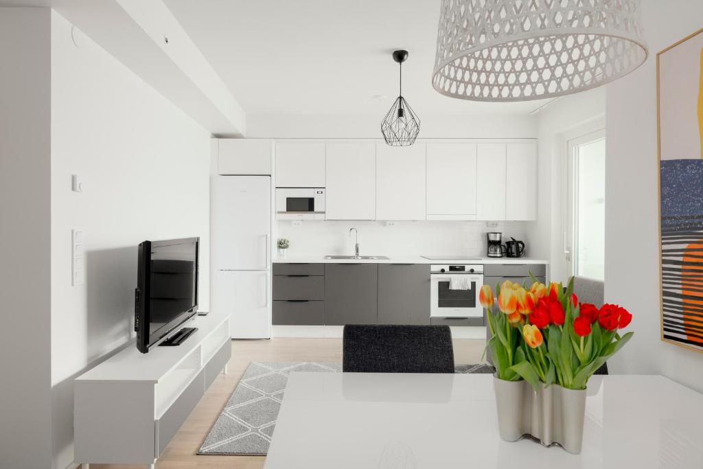赫尔辛基Modern LUXUS 3BR apartment Helsinki Tripla的白色的厨房,配有桌子和花瓶