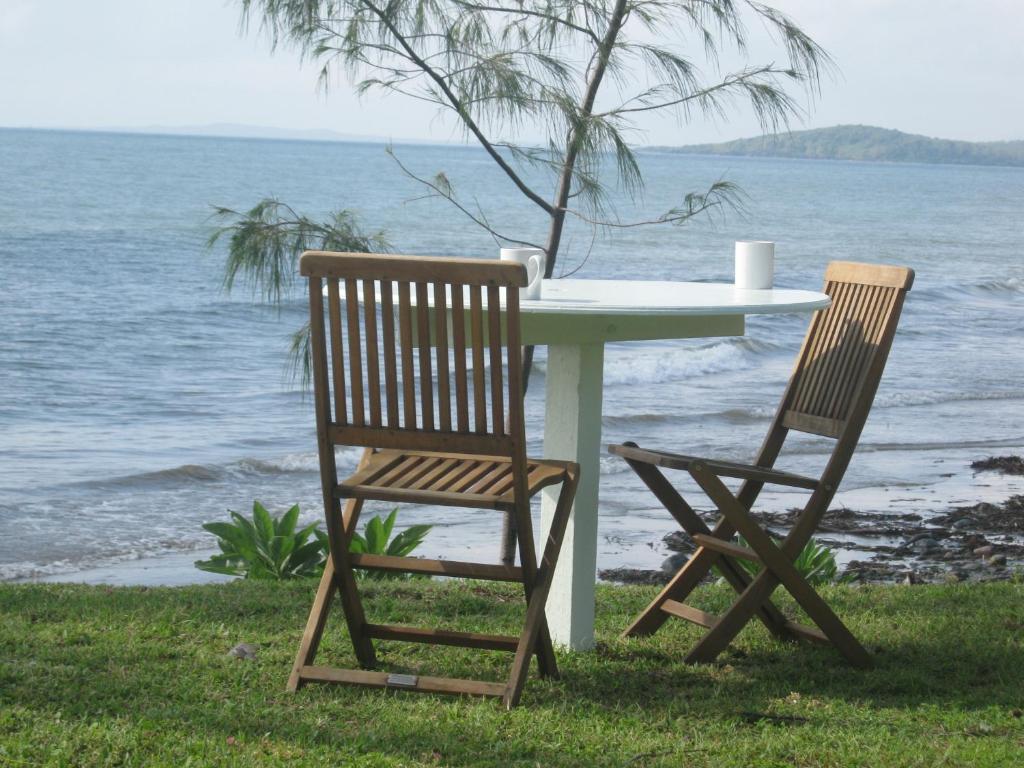 Sarina坎普温海滩度假屋的一张桌子和两把椅子坐在海边